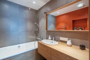 A modern bathroom with a bathtub, a sink, and a mirror. - Easyrooms Dzirnavu (Riga)