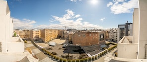 A panoramic view of a cityscape with a mix of modern and traditional buildings, a clear sky, and a parking area. - Easyrooms Dzirnavu (Riga)
