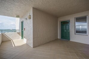 A balcony with a view of the sea, a green door, and a tiled floor. - Dimucci Twin Towers 1105 (Daytona Beach Shores)