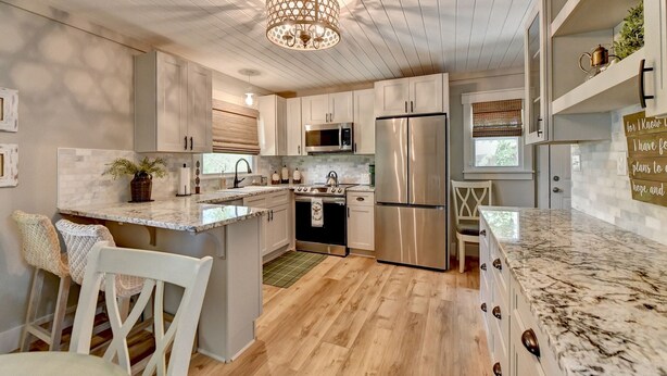 A modern kitchen with white cabinetry, a stainless steel refrigerator, a microwave, and a large island with a sink. - A Southern Retreat / Cozy Getaway in the heart of Atlanta Sleeps 4 (Atlanta)