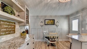 A kitchen with white cabinetry, a marble countertop, a dining table with chairs, and a wall-mounted light fixture. - A Southern Retreat / Cozy Getaway in the heart of Atlanta Sleeps 4 (Atlanta)