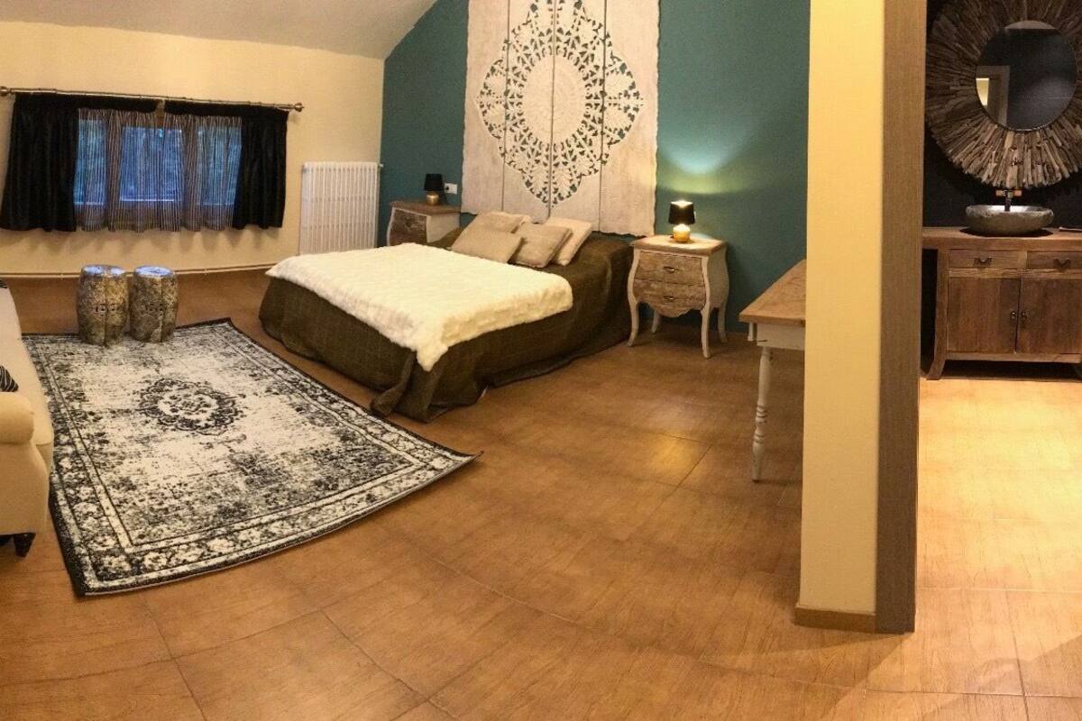 A compact bedroom with a bed, a sofa, a small table, and a decorative mirror.