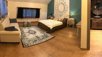 A compact bedroom with a bed, a sofa, a small table, and a decorative mirror.