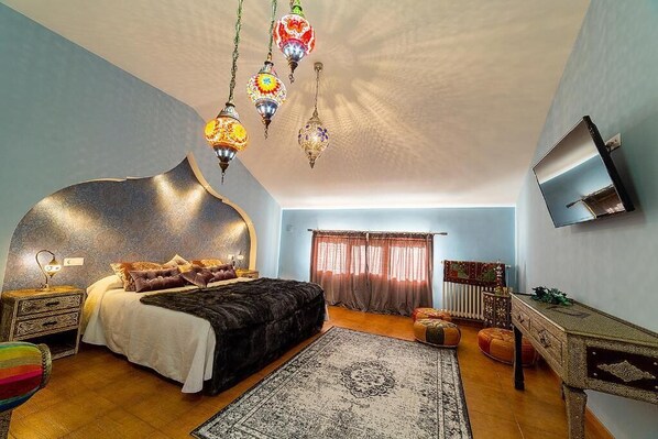 Quarto com uma cama grande, televisão na parede e um design de teto singular.