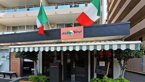 A restaurant named 'arancino' with a closed sign, outdoor seating, and Italian flags.