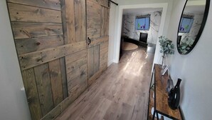 A hallway with a wooden sliding barn door, a marble fireplace, and a mirror on the wall. - Ridgefield Estate, 5BED, Backyard, Games (Plano)