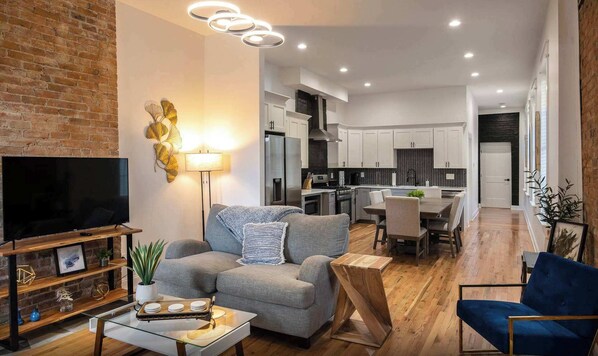 Ein modernes Wohnzimmer mit grauem Sofa, Flachbildfernseher und Couchtisch.