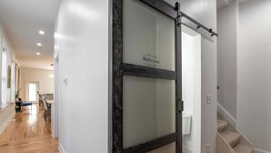 A modern interior with a sliding glass door labeled "Bathroom" leading to a staircase. - Two Condos for 14 Guests, 5 Bedrooms, Free Parking (Covington)