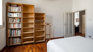 Un dormitorio con una cama grande, una estantería de madera llena de libros y un armario.