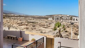 Un balcon donnant sur un paysage désertique, avec un cactus et un palmier.