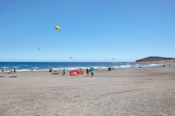 A beach with people, kites, and the ocean.