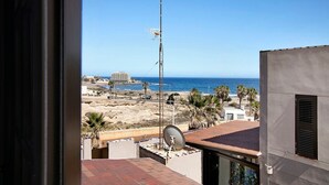 Un balcon avec une antenne parabolique, une grande antenne et une vue sur la plage et l’océan.