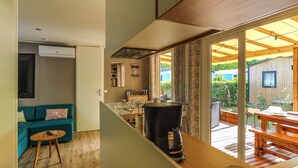 A compact kitchen with a coffee maker, a small dining table, and a sofa in the adjacent living area.
