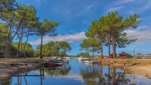 A calm water body with boats docked, surrounded by trees and a small building.