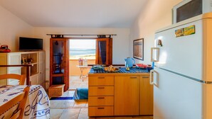 A compact kitchen with a refrigerator, a television, and a dining area with a table and chairs.