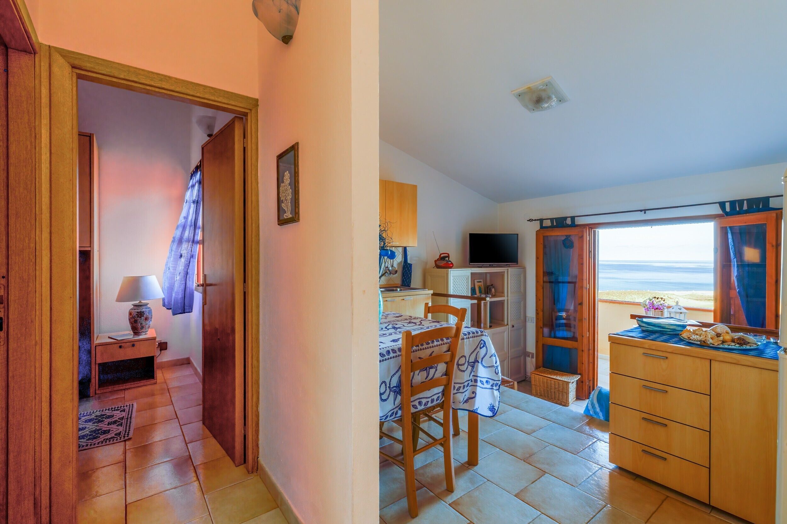 Una stanza con un letto, un tavolo, una TV e vista sul mare.
