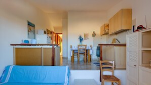 A compact room with a bed, a small table, a chair, a kitchenette, and a dining area.