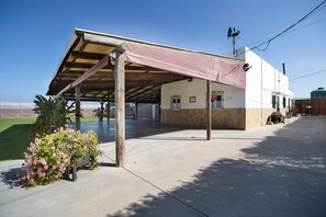 A covered outdoor area with a building, a water tank, and a garden. - Country House 'Villa Pastrana' with Private Terrace, Wi-Fi, and Air Conditioning (Chipiona)