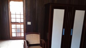 A room with a bed, a wooden wardrobe, a chair, and a door leading outside. - Vacation Home 'Chalet Rural Marian' with Sea View, Garden & Wi-Fi (Santa María de Guía)