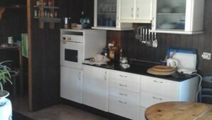 A compact kitchen with white cabinets, a microwave, a coffee maker, and a wooden table. - Vacation Home 'Chalet Rural Marian' with Sea View, Garden & Wi-Fi (Santa María de Guía)