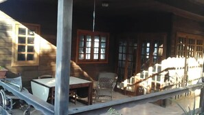 A wooden house with a porch, a table, a chair, and a wheelchair. - Vacation Home 'Chalet Rural Marian' with Sea View, Garden & Wi-Fi (Santa María de Guía)