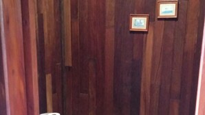 A bathroom with a white toilet, wooden panel walls, and a tiled floor. - Vacation Home 'Chalet Rural Marian' with Sea View, Garden & Wi-Fi (Santa María de Guía)
