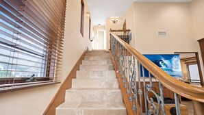 A staircase with a wooden handrail and metal balusters, leading to a landing with a large painting and a door.
