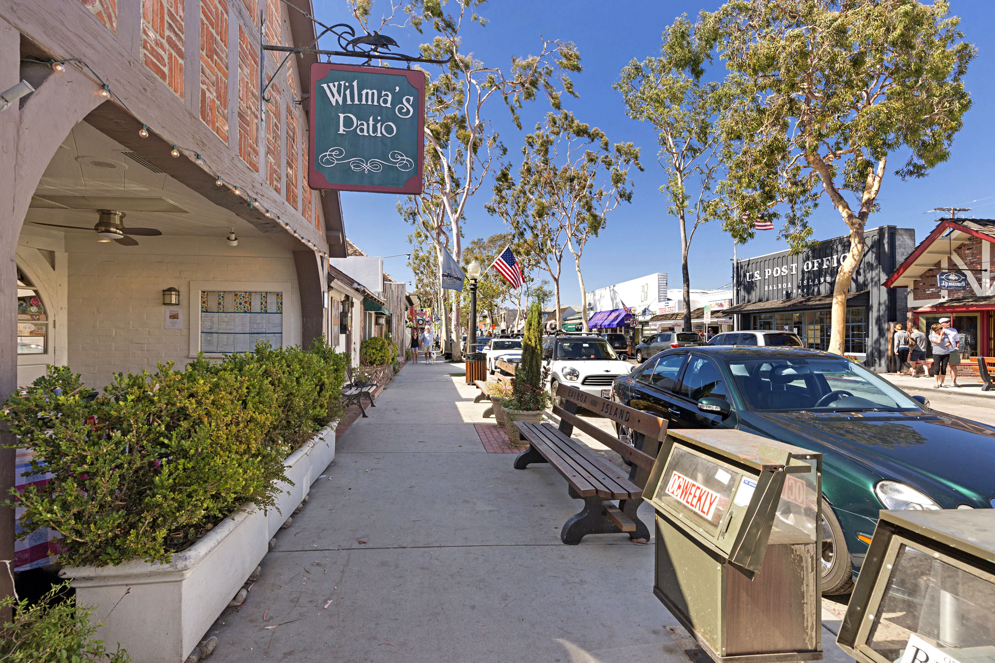 Une rue avec une enseigne indiquant «Wilma’s Patio» et un bureau de poste américain.