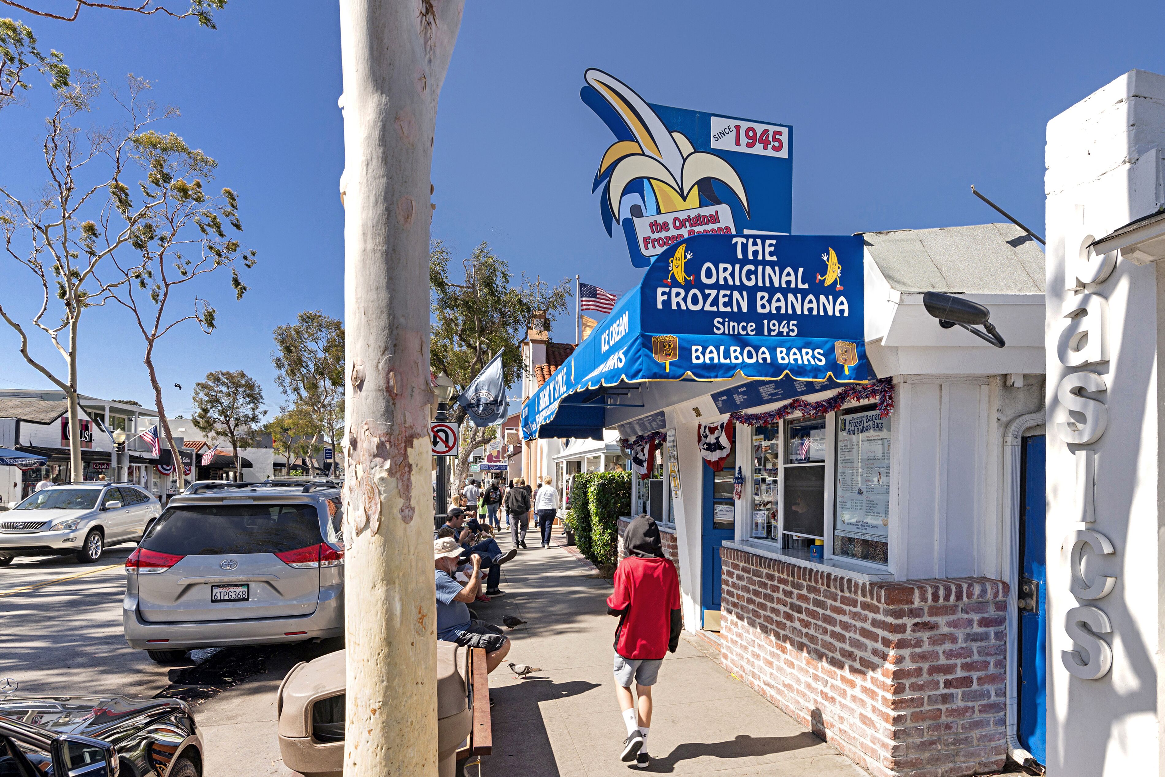 A street scene with a blue sign for 'The Original Frozen Banana' and a brick building with a blue door.