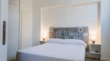 A neatly made bed with white linens in a room with a patterned tile headboard. There are two bedside tables with lamps.
