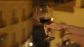 Une main tenant un verre à vin, avec une rambarde et des bâtiments en arrière-plan.