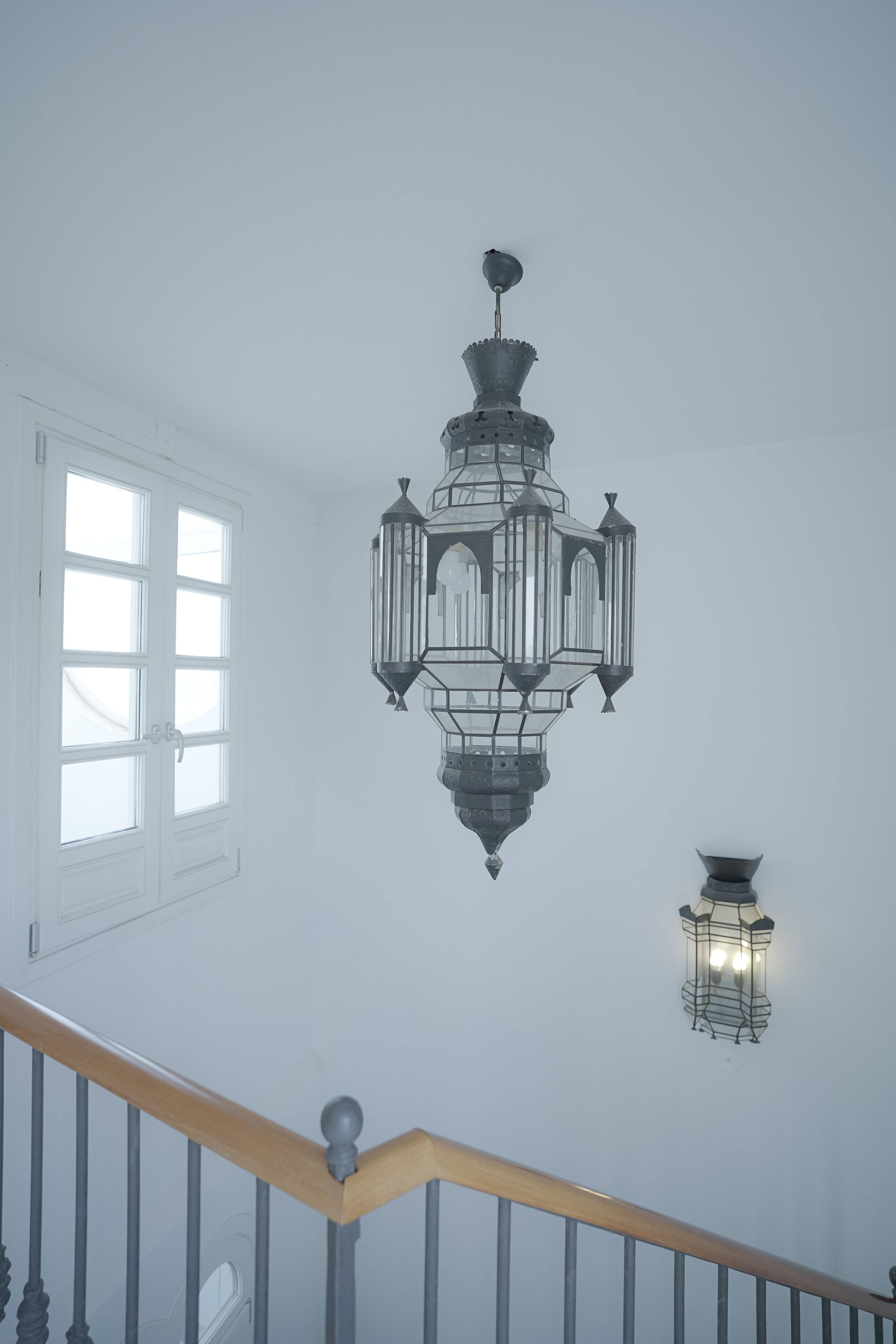 A chandelier with multiple glass panels and a wall-mounted light fixture.