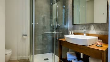 A modern bathroom with a glass shower enclosure, a white sink, and a wooden vanity.
