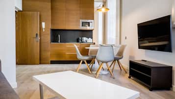 A modern kitchen with wooden cabinets, a microwave, and a dining area with a white table and grey chairs.