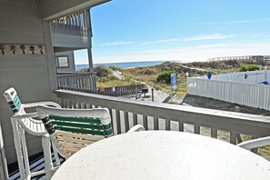 Un balcon avec vue sur la plage, une table et des chaises.