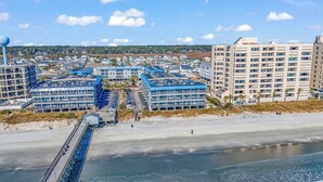 Un hotel a la costa amb diversos edificis, una platja i un moll.