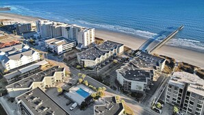 Vista aèria d'una zona hotelera costanera amb diversos edificis, una platja i un moll.