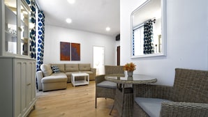 A living room with a sofa, a glass-top table, wicker chairs, and a cabinet. - CASA VERDE Comfortable Air-Conditioned (Ingenio)