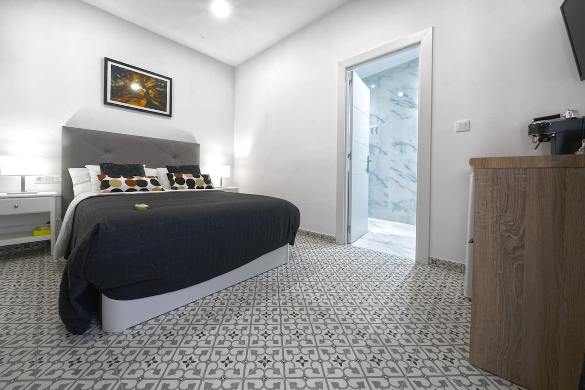 A bedroom with a bed, bedside table, and a nightstand.