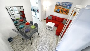 A compact living space with a dining area, a red sofa, and a kitchen in the background. - CASA VERDE Comfortable Air-Conditioned (Ingenio)