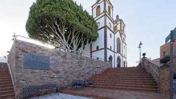 A staircase leading to a church with a bell tower, a plaque on the wall, and a bench.