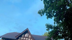 Ein zweistöckiges Haus mit Satteldach, einer Veranda und einer Ziegelauffahrt.