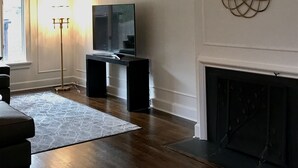 Ein Wohnzimmer mit Kamin, Fernseher und einem dekorativen Spiegel an der Wand.