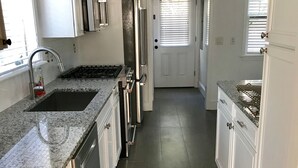 Eine moderne Küche mit Granit-Arbeitsplatten, Edelstahlgeräten und weißen Schränken.