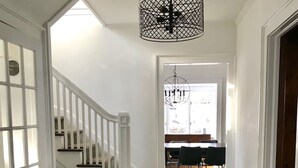 Eine Treppe mit weißer Handläufung führt zu einem Essbereich mit einer Kandelaberleuchte.
