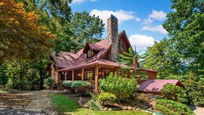 A rustic cabin with a stone chimney, wooden porch, and a well-maintained garden.