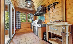 A wooden cabin interior with a kitchen area featuring a grill, a sink, and a welcome sign.