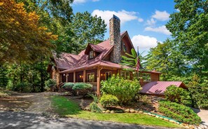 A rustic cabin with a stone chimney, wooden porch, and a well-maintained garden.