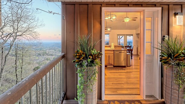 Ein Balkon mit Landschaftsblick, Holzboden im Inneren und ein durchgehender Blick in den Küchenbereich.