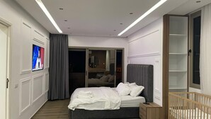 Et moderne soveværelse med seng, natbord, tremmeseng og en skydedør til en balkon.